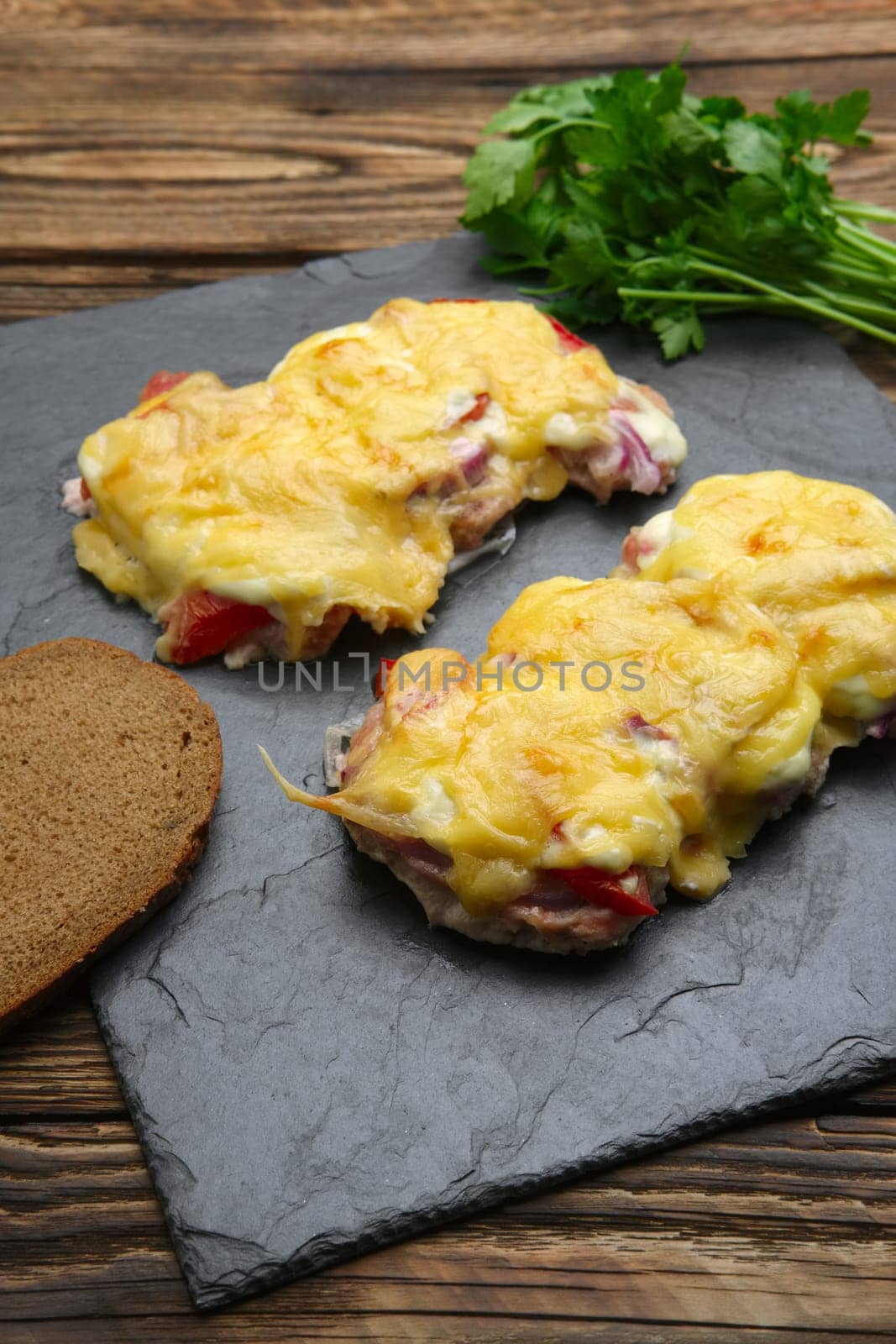 Baked in oven meat with mushrooms, tomato and cheese, servet on stone plate