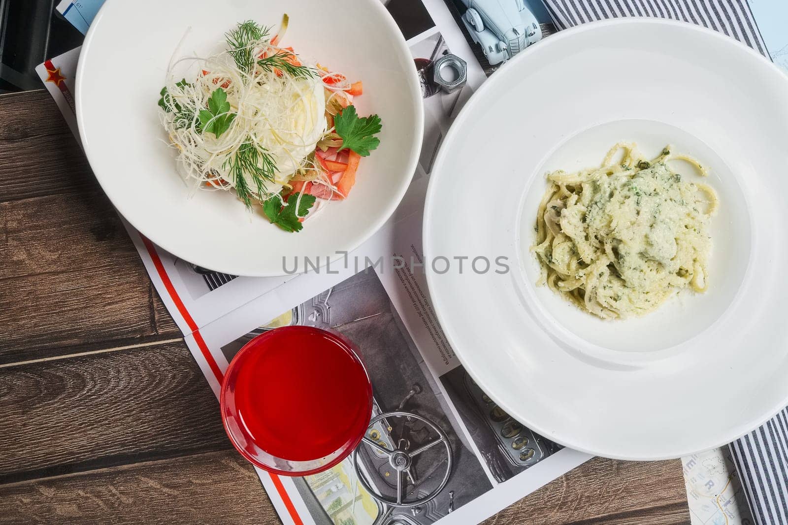 Glass of fruit-drink, and cheese and vegetables salad on the table. Top point of view.