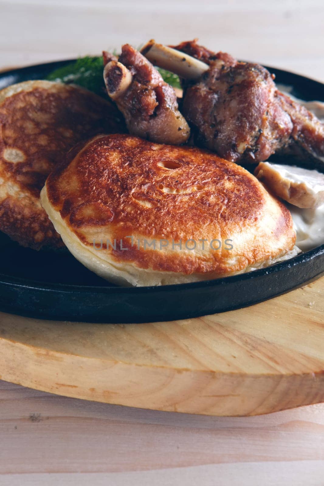 Fried in oven rabbit with fritters and onion sauce. Cast iron pan on wooden cutting board