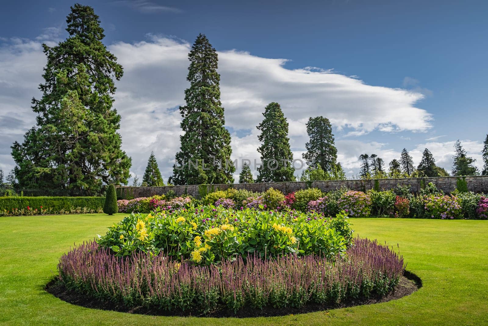 Circular flowerbed in beautiful Powerscourt garden with hedges, decorative trees, fountains and forest, Enniskerry, Wicklow, Ireland