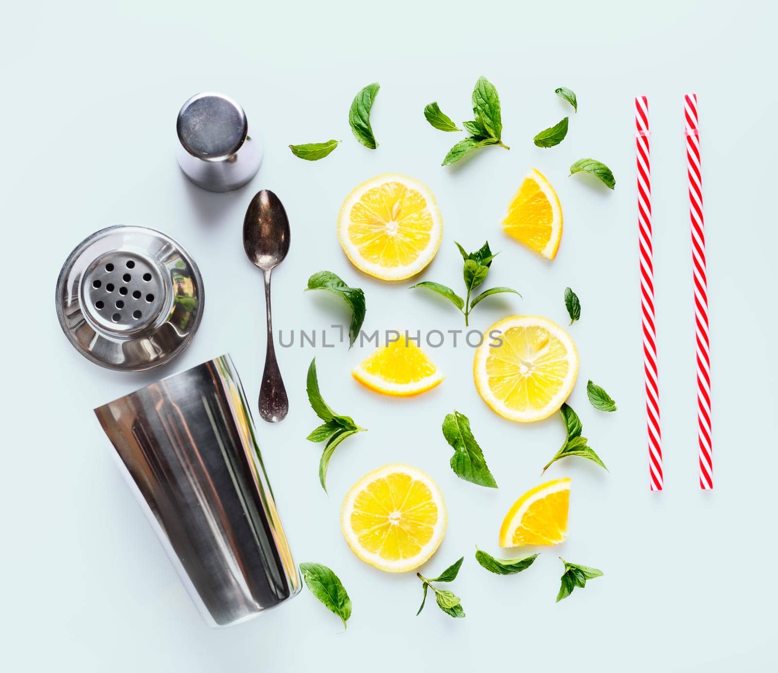 Top view of citrus slices, mint herbs and cocktail shaker on retro mint background.