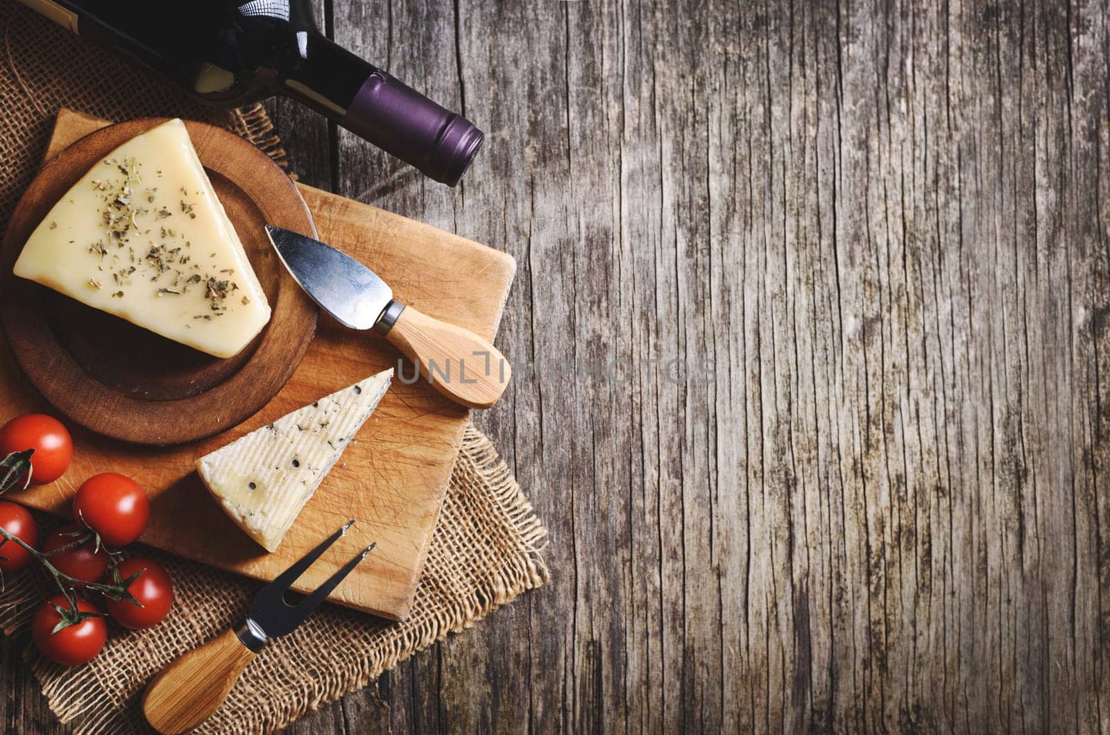 Top view of red wine and cheese on rustic wooden background with copyspace. French cuisine product..