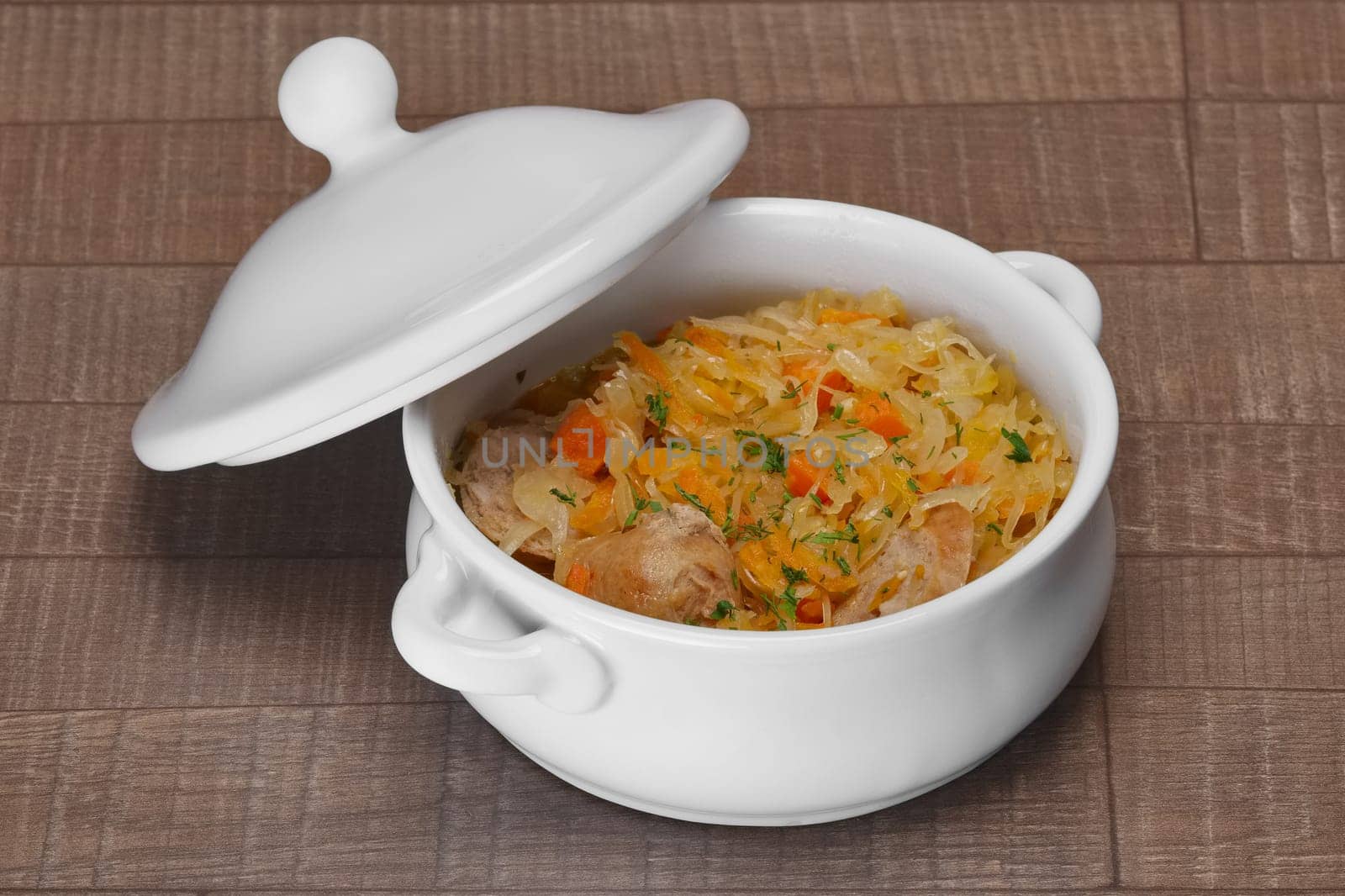 White bowl with homemade sausage and pickled cabbage baked in oven on wooden table