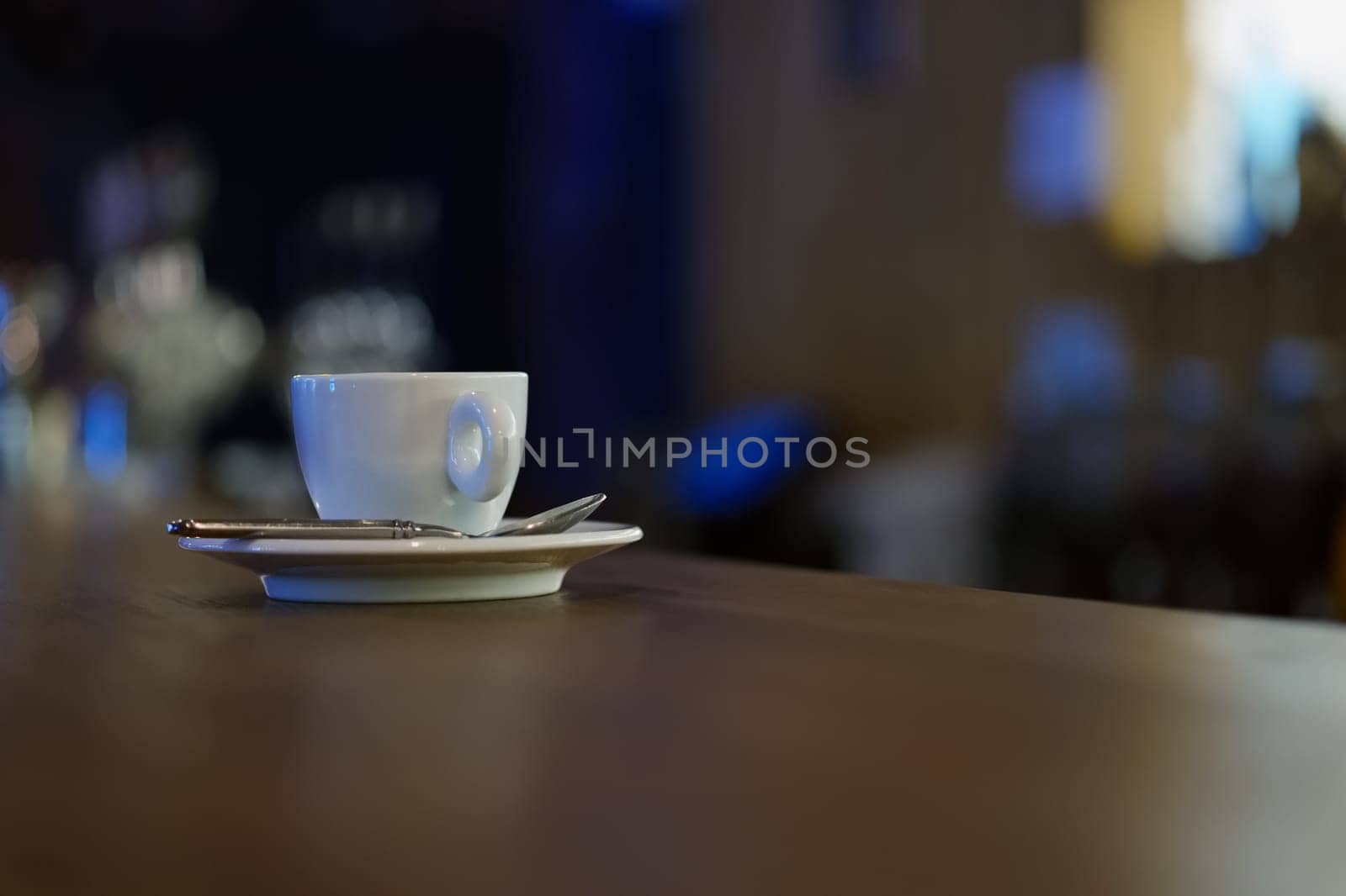 White cup of coffee with steam on wooden table near window