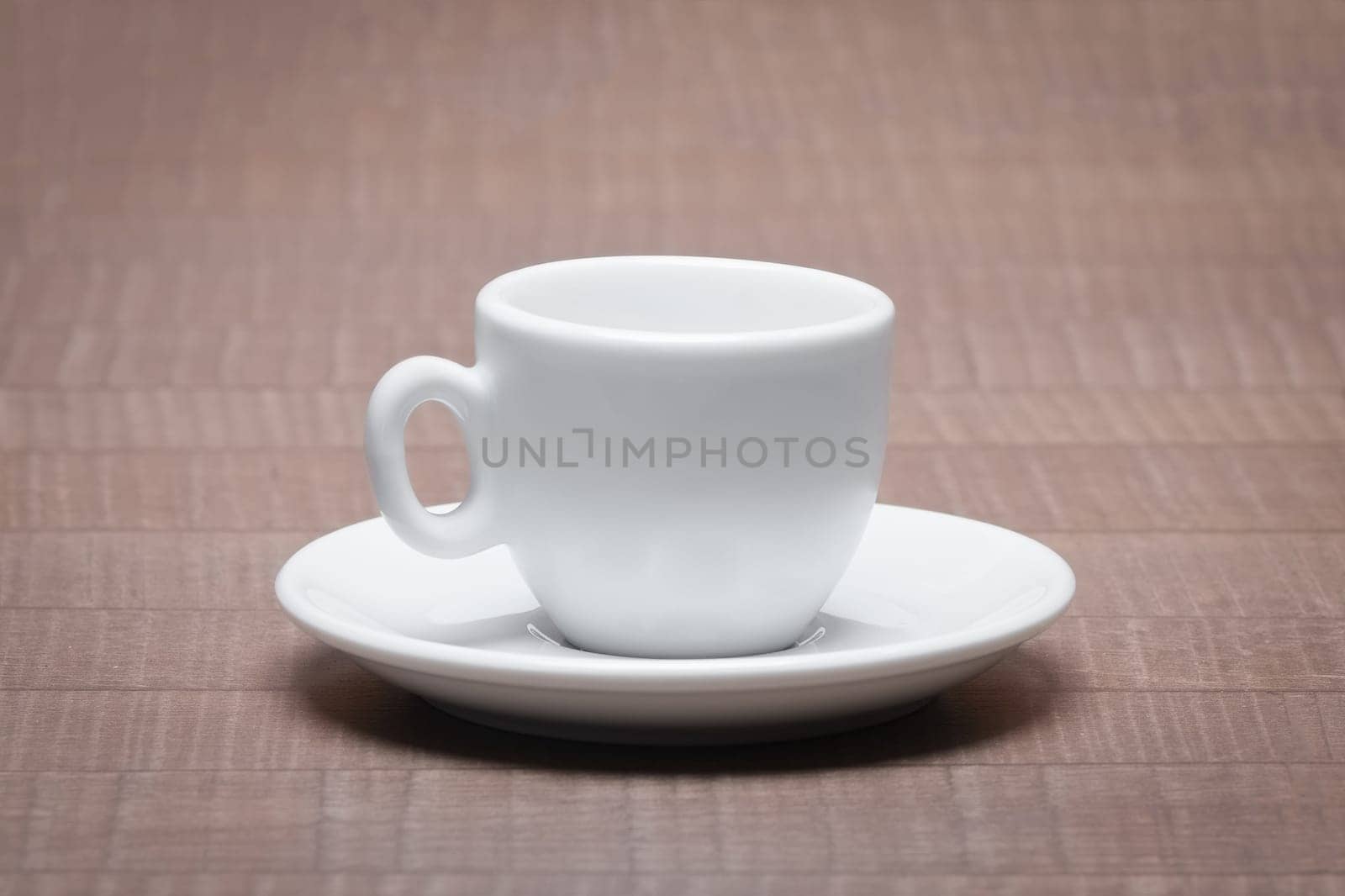 Clean and empty ceramic cup for espresso with saucer on wooden table.