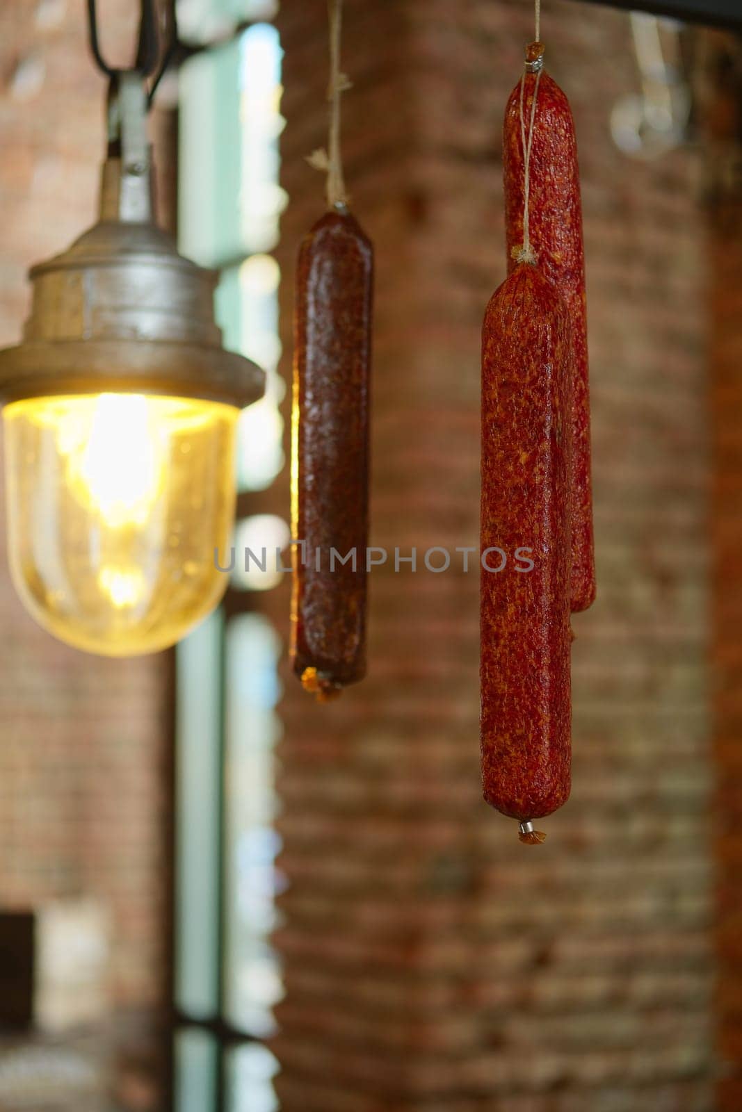 Smoked  sausagees hanging on a hook under the ceiling. Photo with shallow depth of field.