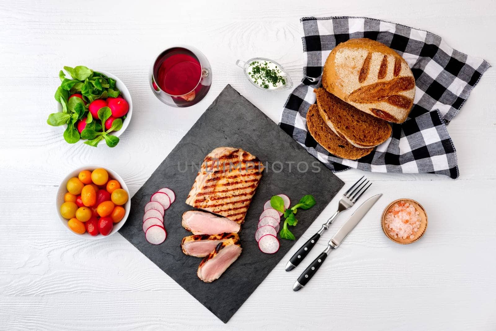 Grilled beef steak medium rare on stone board with fresh vegetables and glass of red wine. View from above.