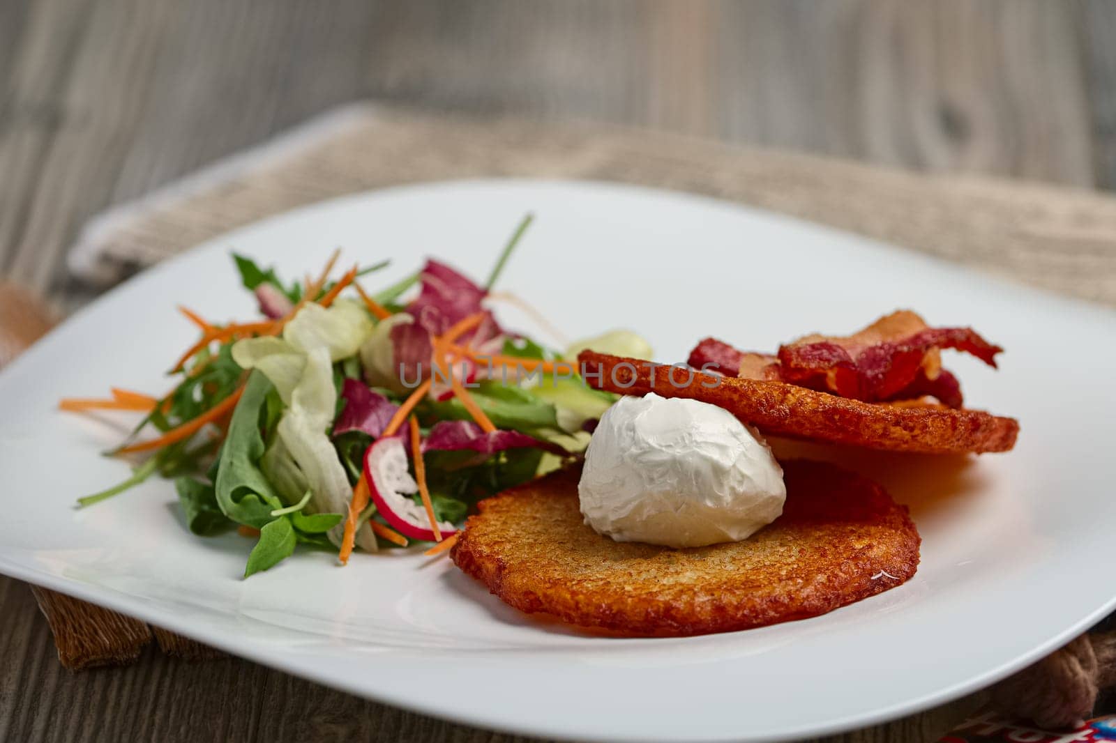 Classic potato pancakes with bacon and salad. Soft focus photo.