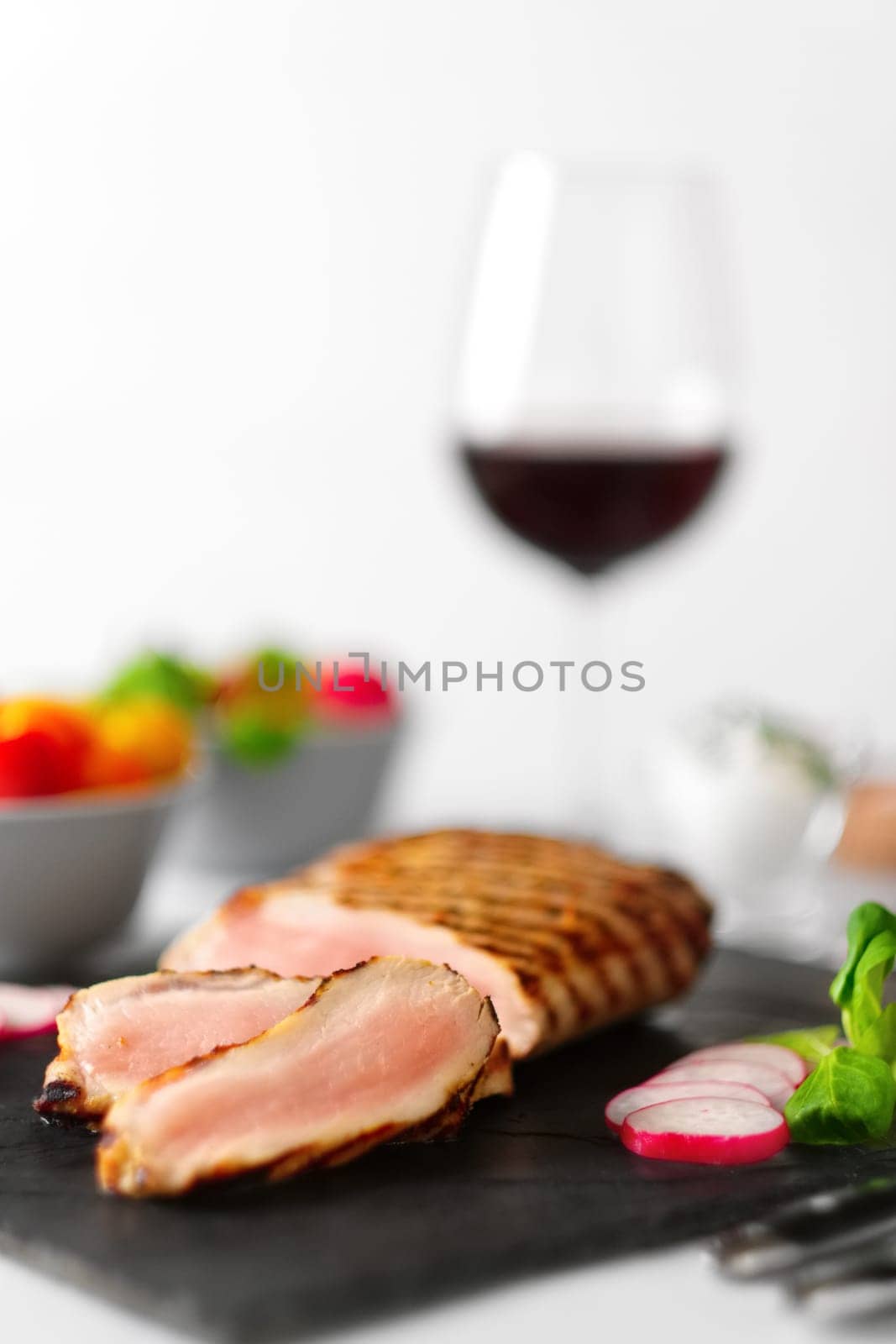 Grilled beef steak medium rare on stone board with fresh vegetables and glass of red wine. Photo with shallow depth of field.