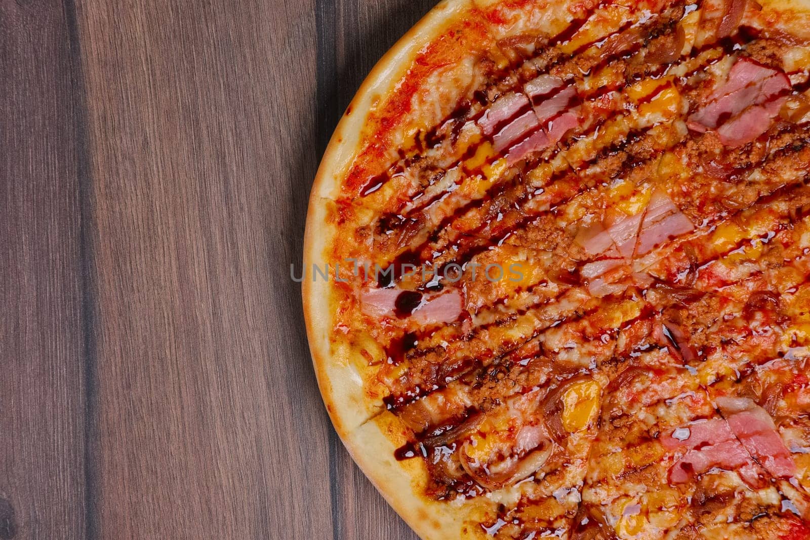 Top view of pizza with ham and balsamic sauce cutted on pieces.