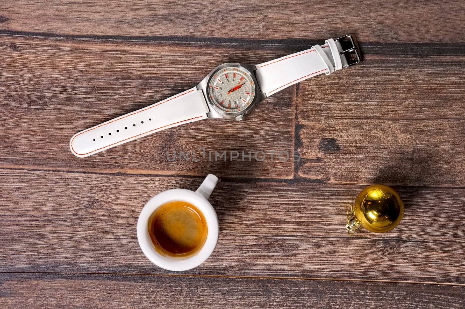 Top view of wrist watch, coffee and christmas tree toy on wooden table