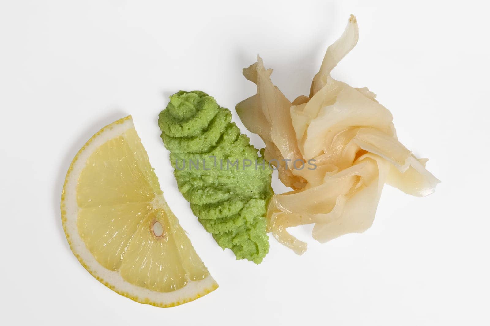 Top view of slice of lemon, wasabi and pickled ginger on white background with shadow.