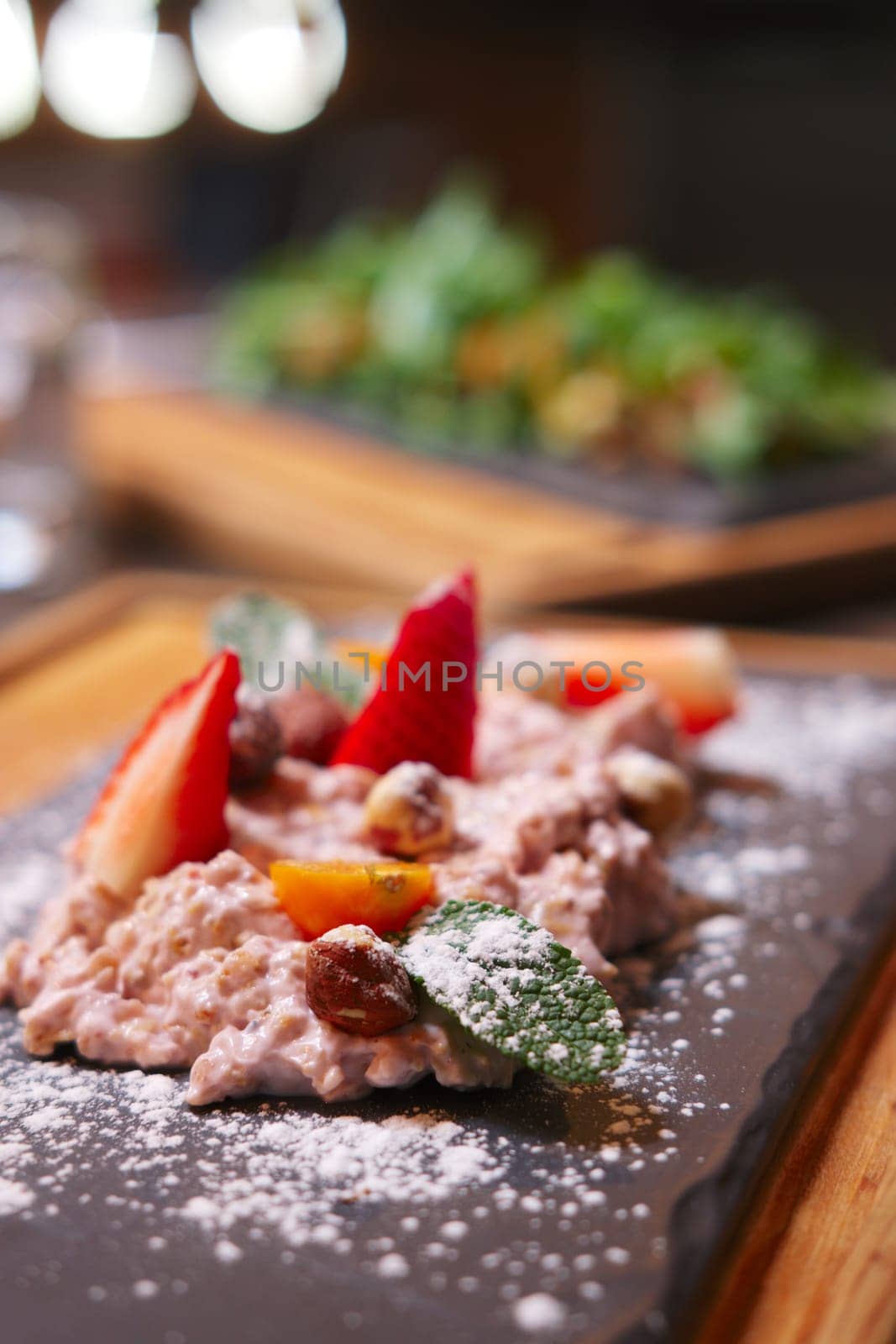 Sweet oatmeal with fruits decorated with sugar powder. Photo taken with shallow depth of field.
