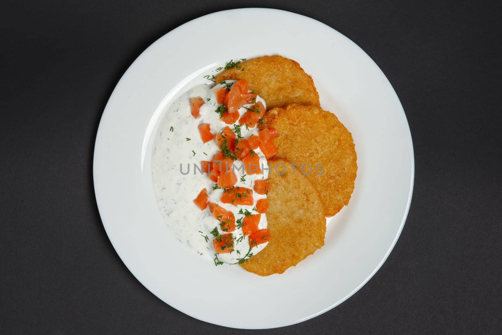 Top view of traditional belorussian potato pancakes with salmon and sour cream