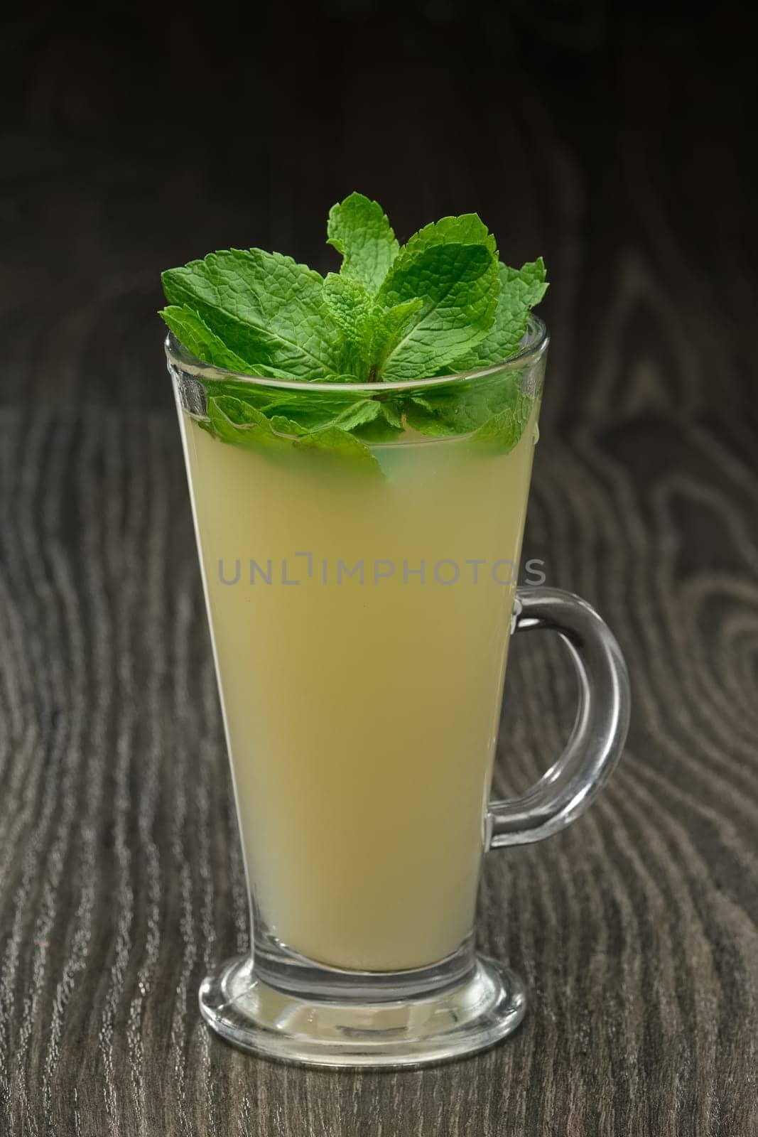Glass of hot tea with ginger, honey, lemon and mint on wooden table