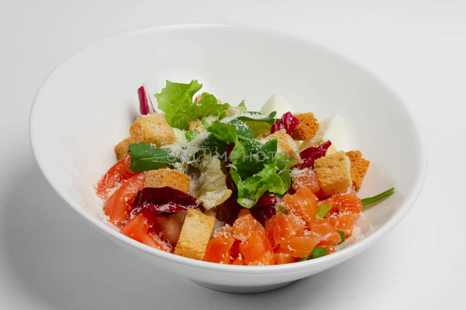 Plate with salmon, tomato and egg salad on white background