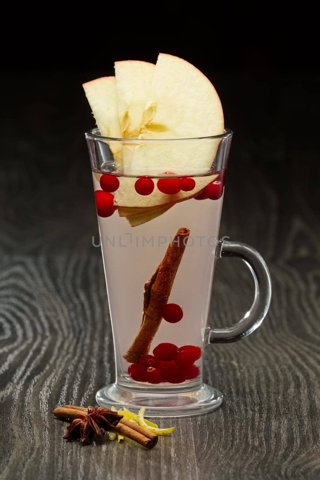 Glass of hot fruit tea with apple, cinnamon and cranberry on wooden table