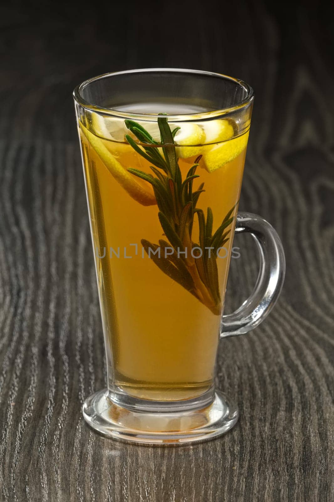 Glass of hot fruit tea on wooden table (soft focus photo)