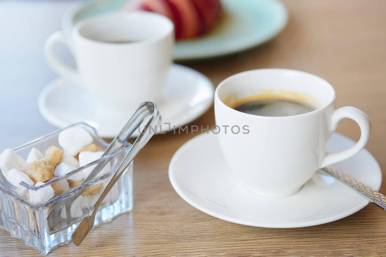 Cup of hot coffee and croissant on background in cafe(photo with shallow depth of field