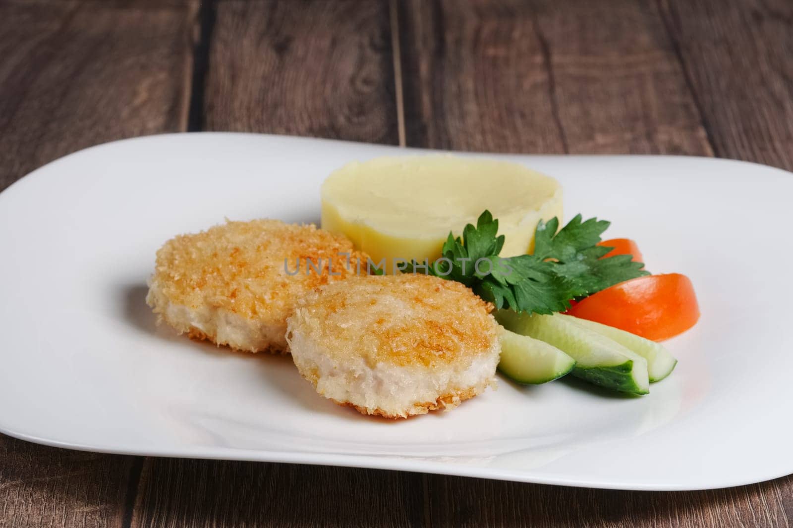 Plate with salmon cutlet with mashed potato and fresh cucumber and tomato
