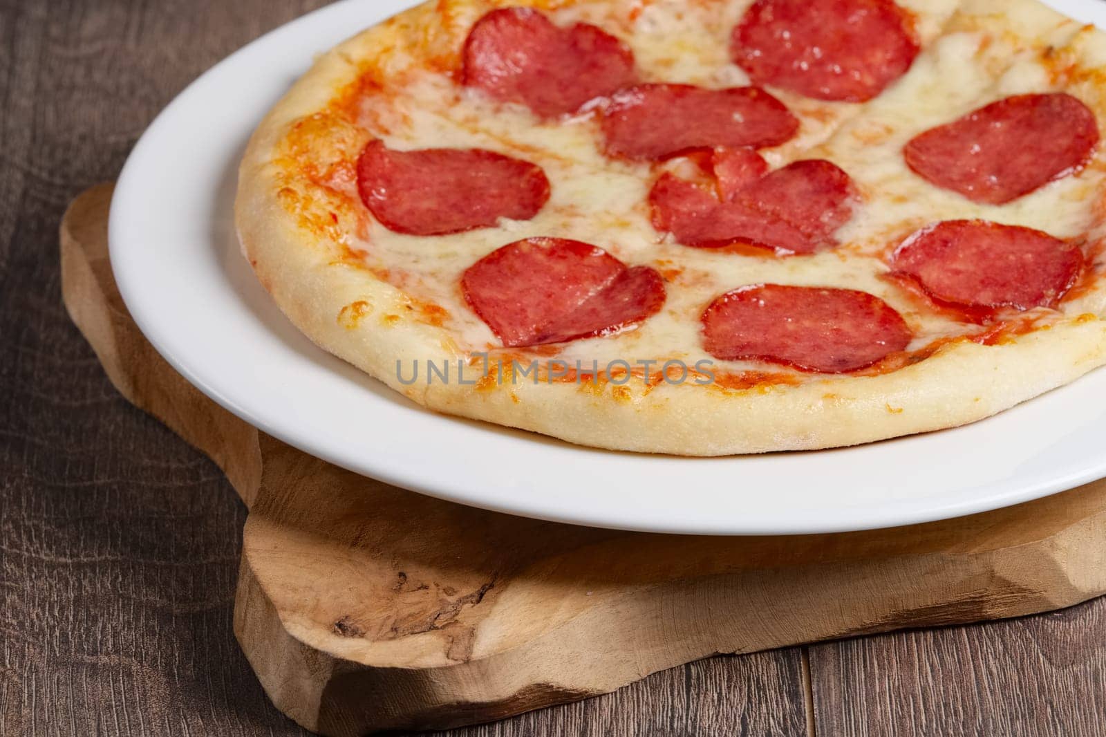 part of pizza pepperoni on wooden plate