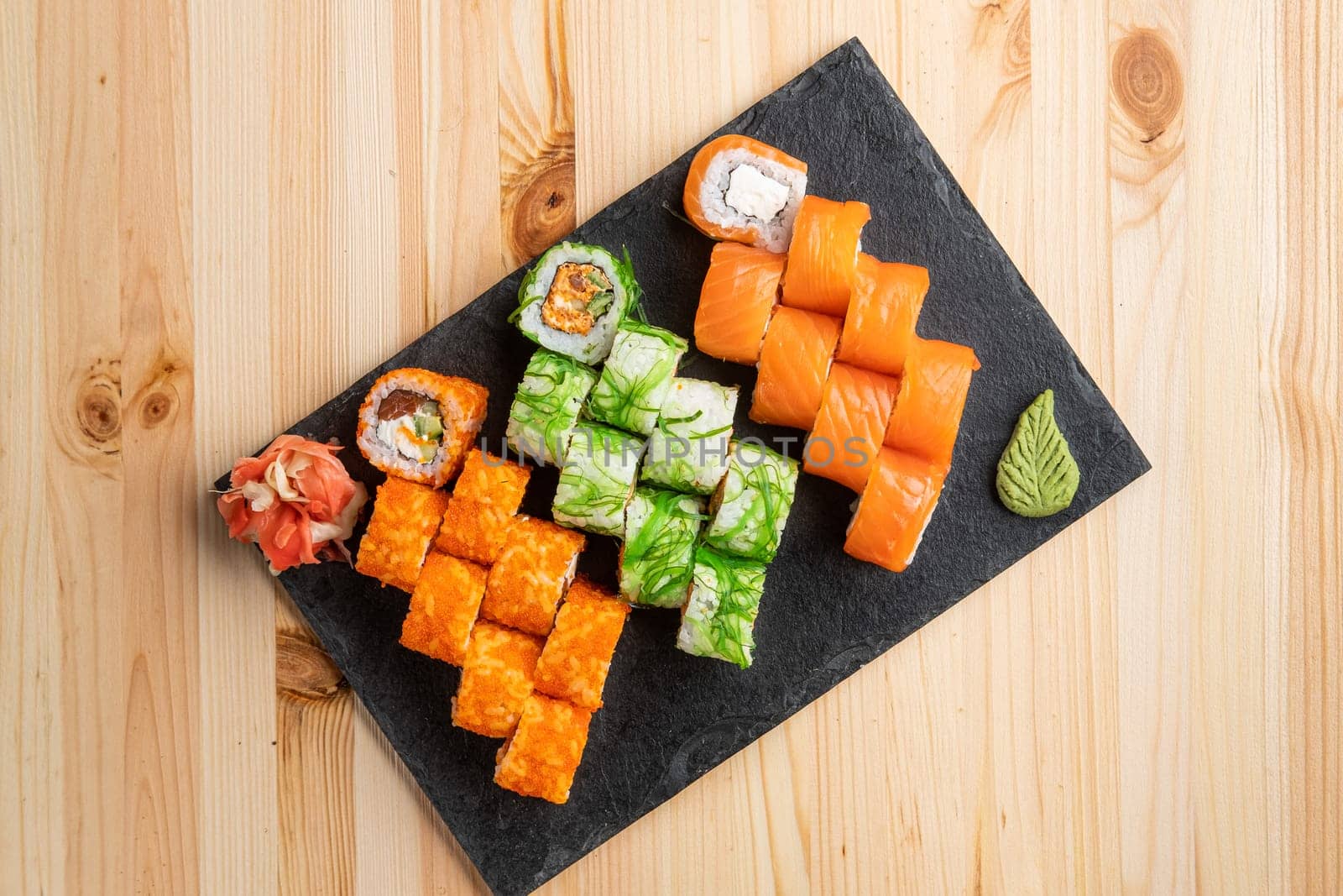 Set of rolls with wasabi and pickled ginger on stone serving board
