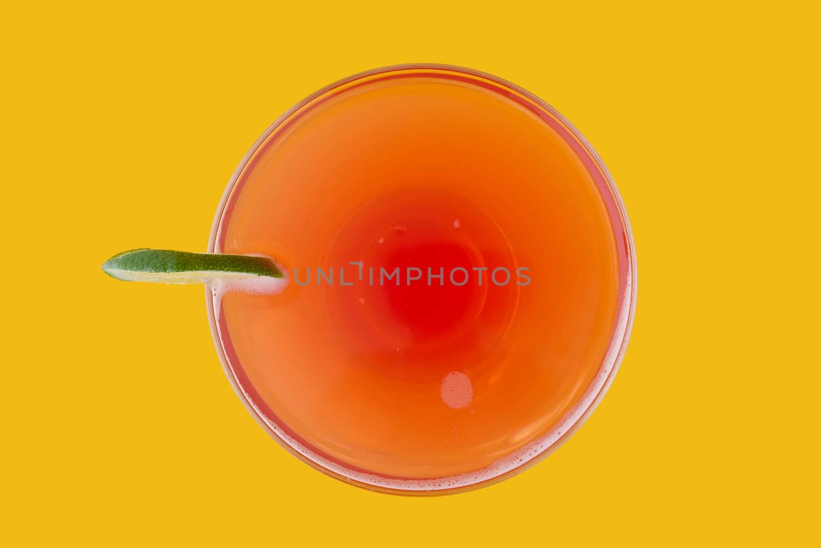 Top view of cosmopolitan cocktail on yellow background