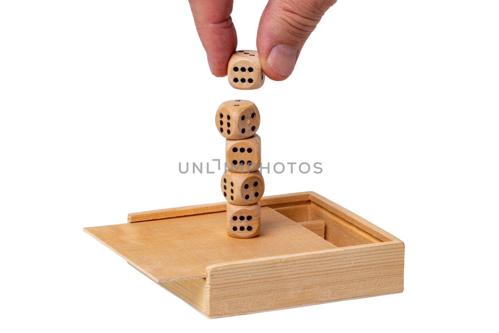 On an open wooden box a hand stacks playing cubes to form a tower. Isolated on white. Macro. Business concept. Mock up.
