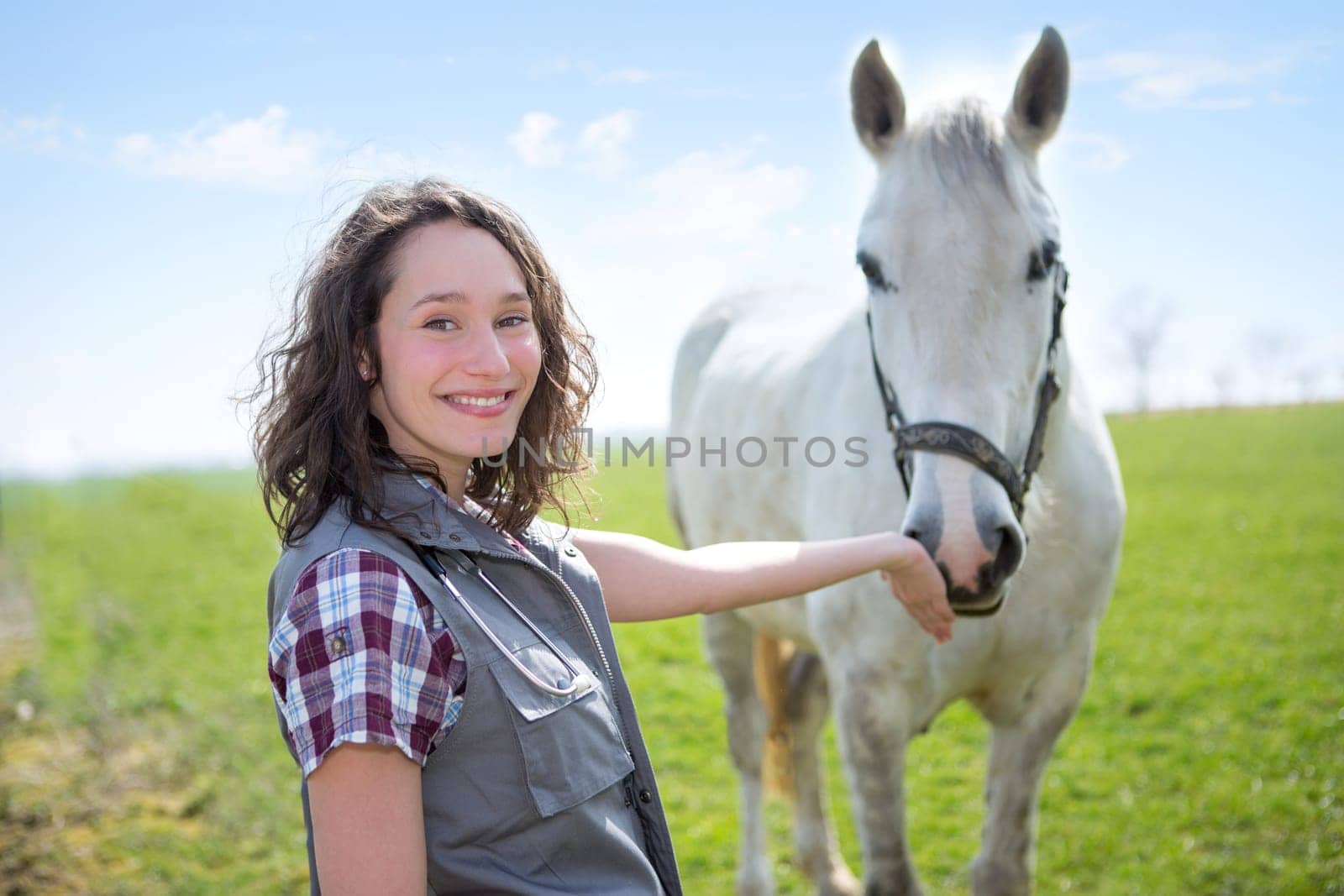 View of a young attractive veterinary in fields with horse