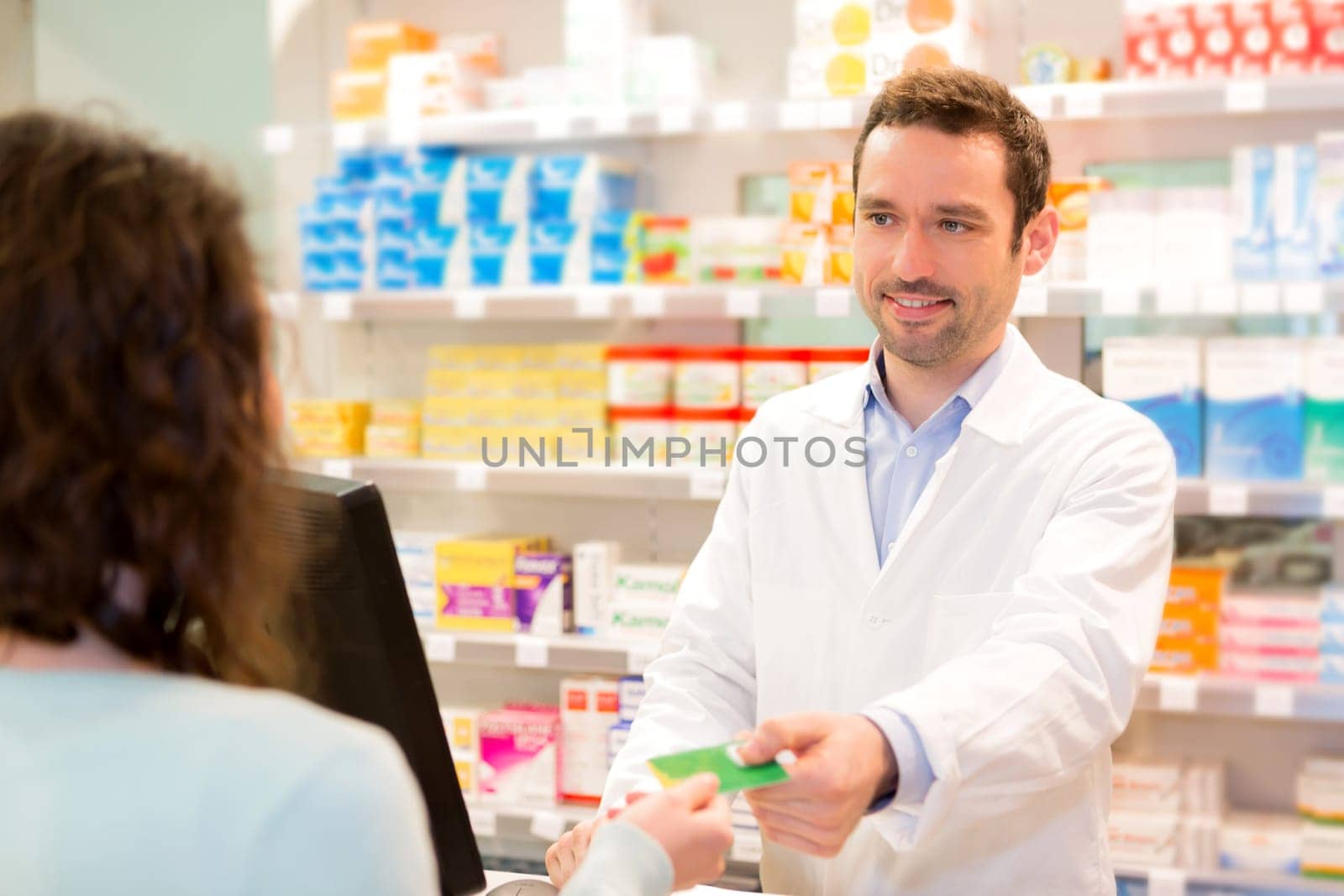 View of an Attractive pharmacist taking healt insurance card
