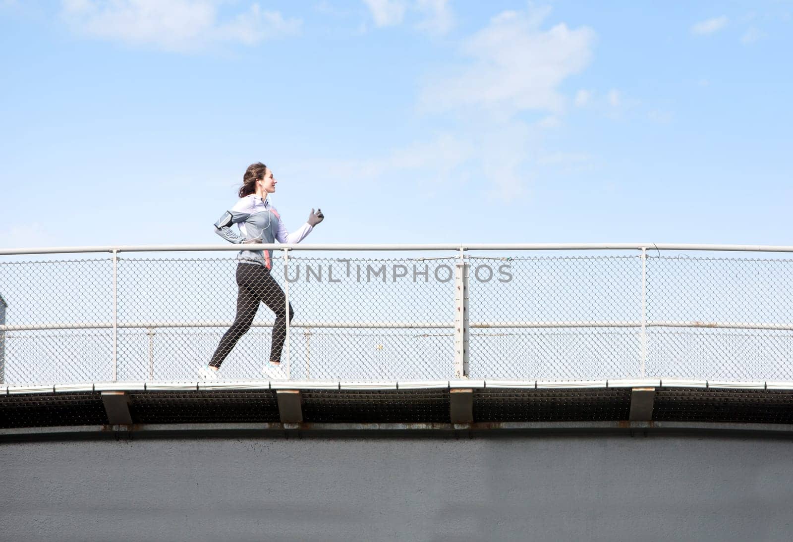 View of a Young attractive woman running on a bridge
