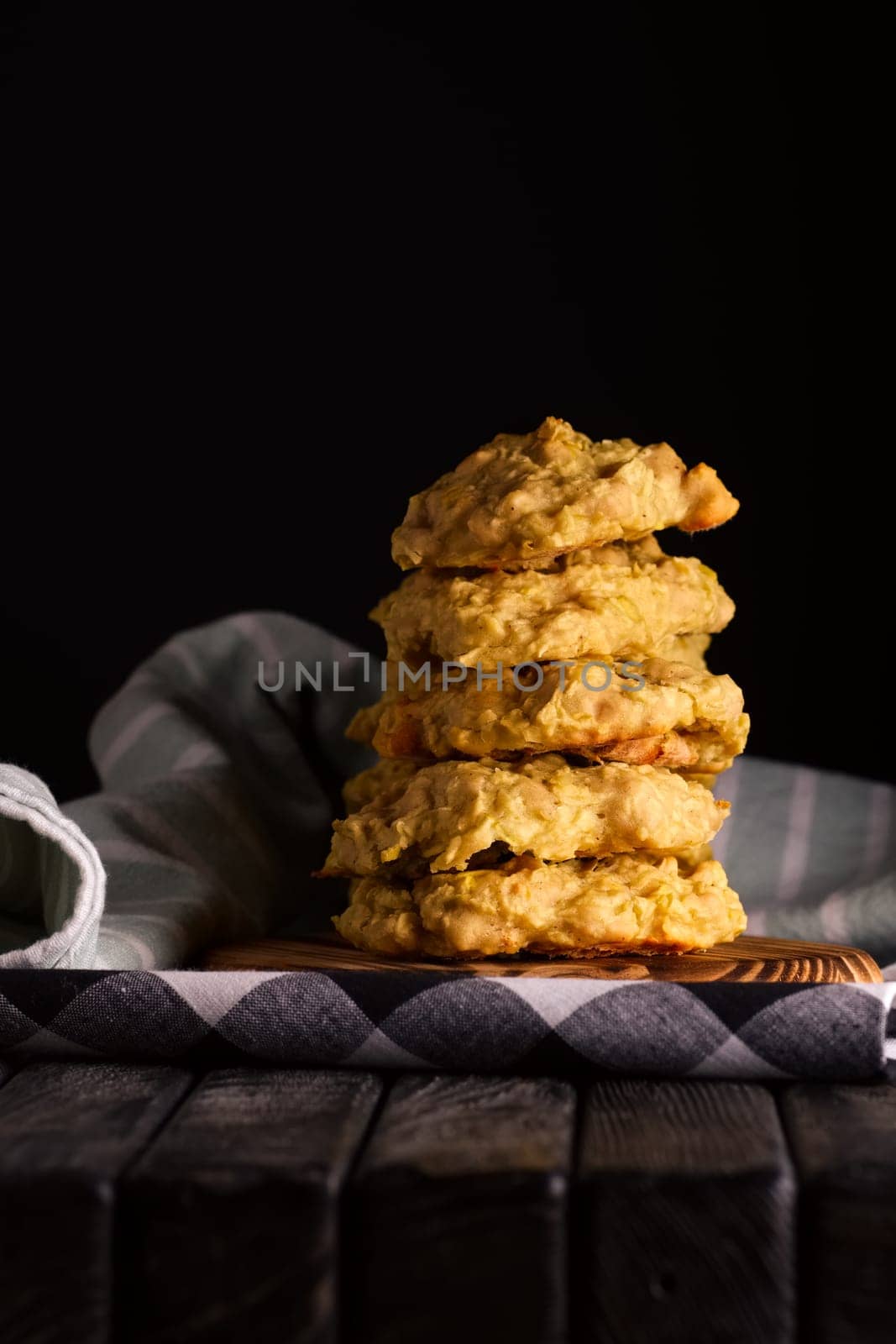 Low key photo of  stack of of ginger, lemon and apple biscuits on wooden table. Chocolate chip cookies on dark wooden background with copy space.