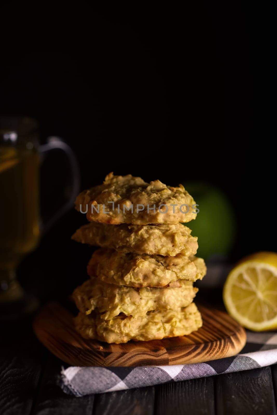 Low key photo of  stack of of ginger, lemon and apple biscuits on wooden table. Chocolate chip cookies on dark wooden background with copy space.