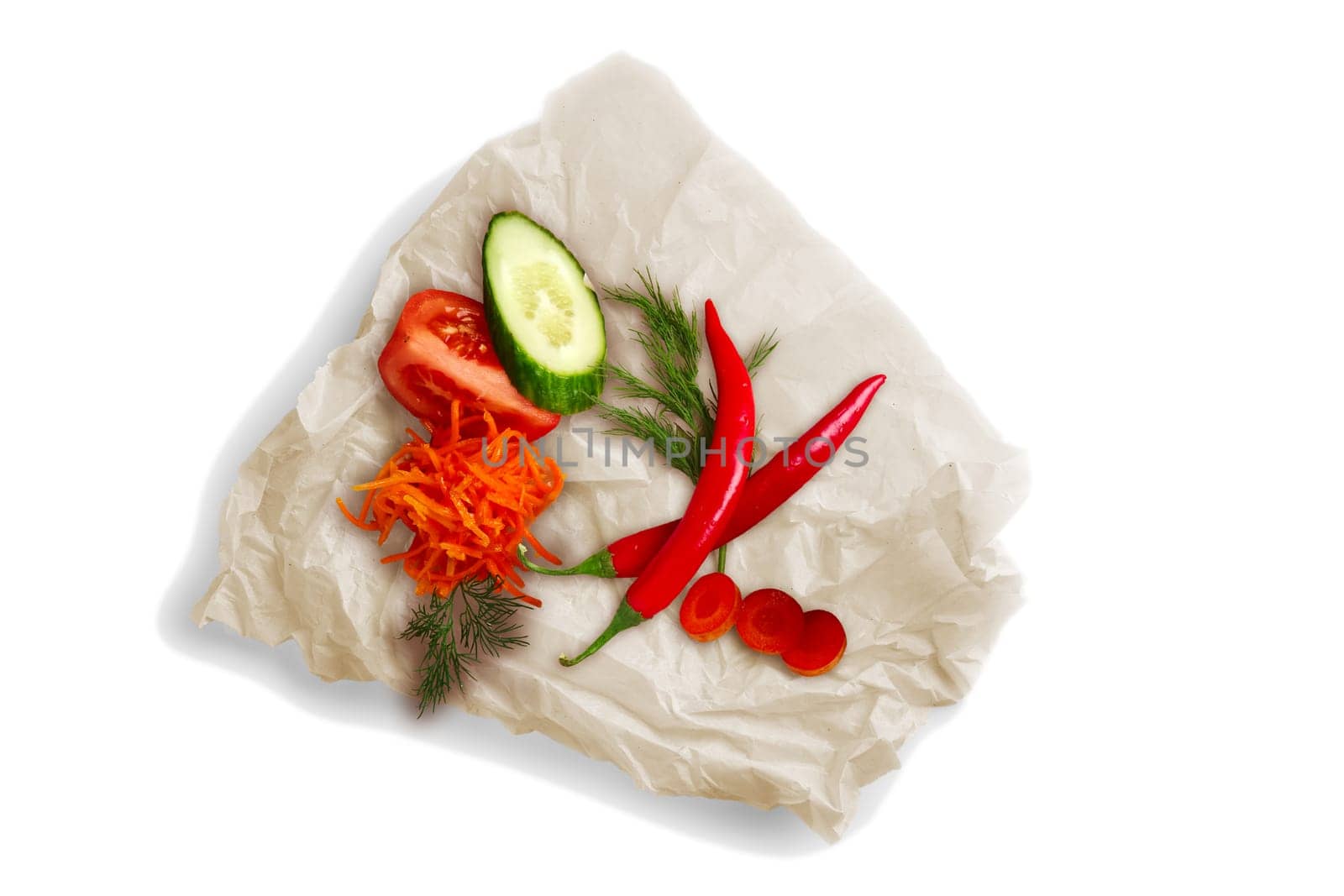 Colorful vegetables on crumpled parchment for baking isolated on white. Ingredients for salad, meal.