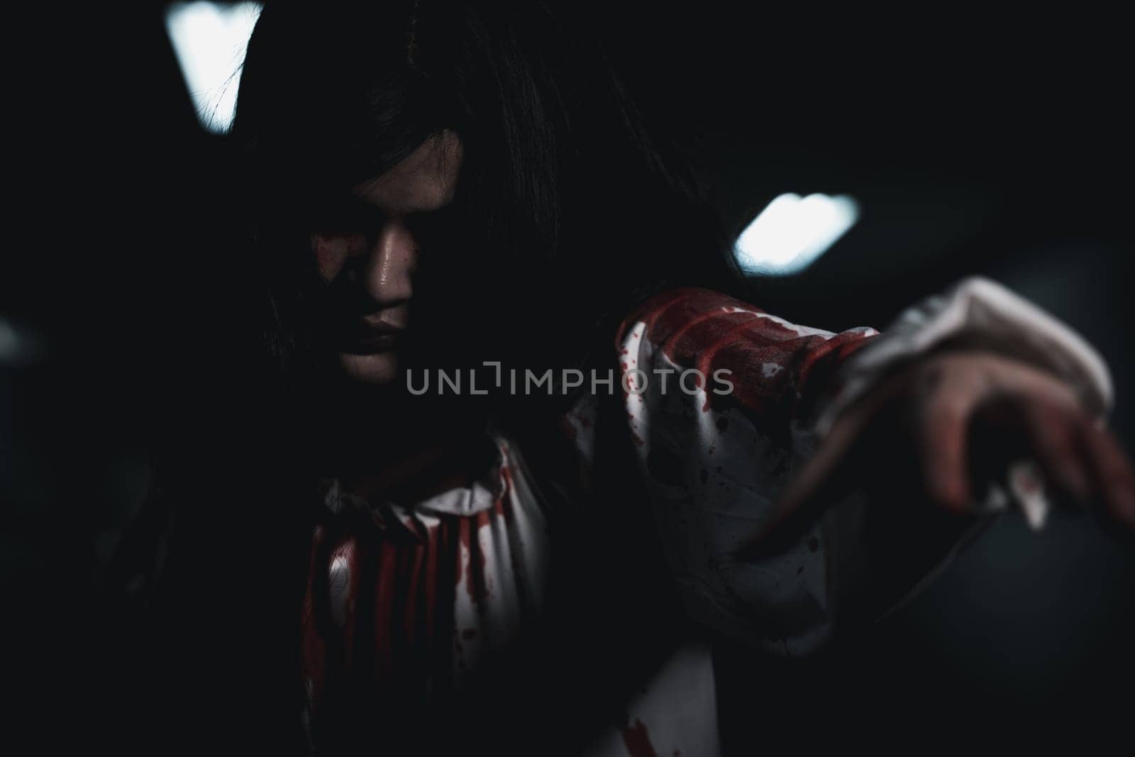 Bloody halloween makeup. Horror bloodthirsty ghost girl hair covering face and eye reach arm out, Asian woman zombie with blood she death and scary at night in tunnel, Happy halloween day concept