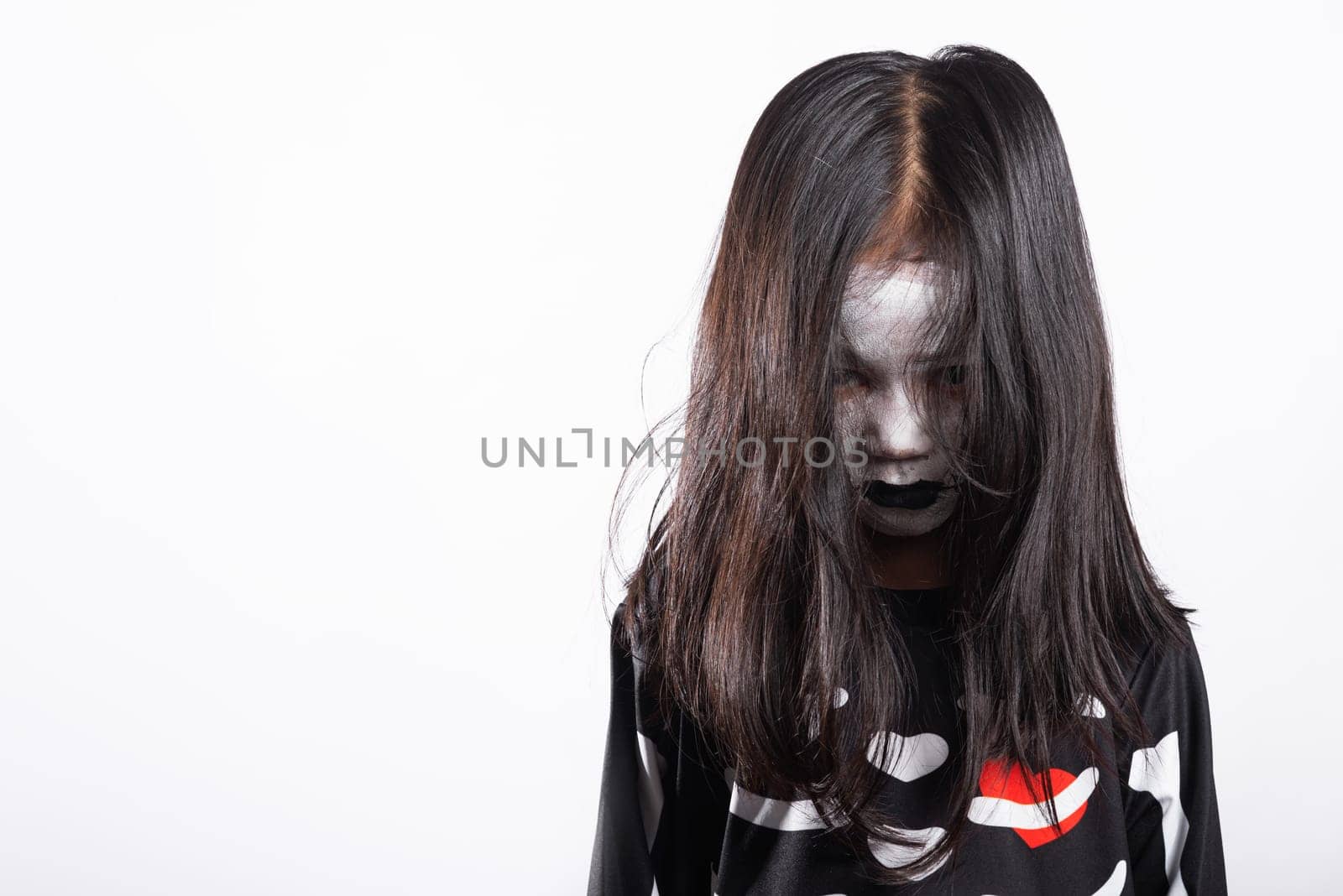 Asian little kid girl with face painting and hair covering face, woman child ghost or zombie horror creepy scary skeleton costume studio shot isolated on white background, Happy Halloween day concept