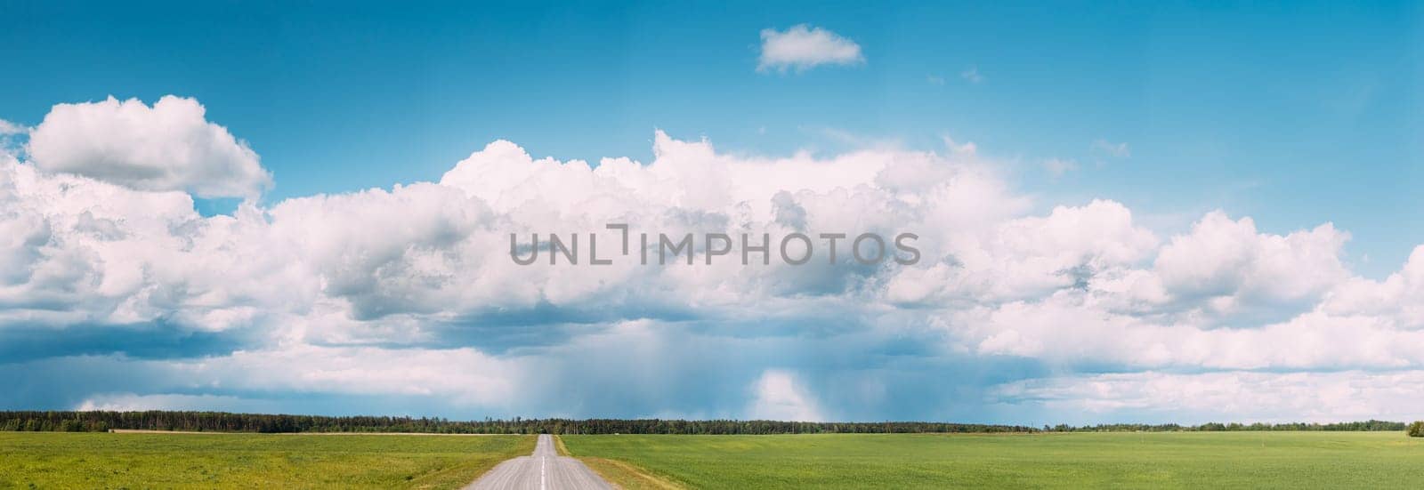 Panoramic View Of Open Asphalt Countryside Road Through Fields Or Meadows. Sunny Day White Clouds On Blue Sky.