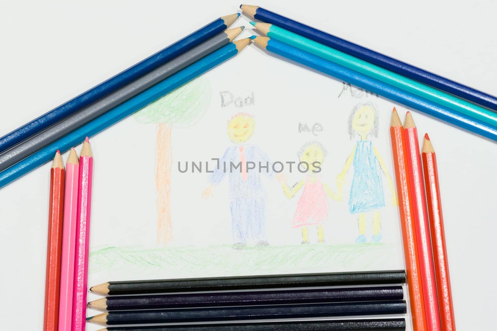 Multicolored pencils at a white paper with a child's family picture
