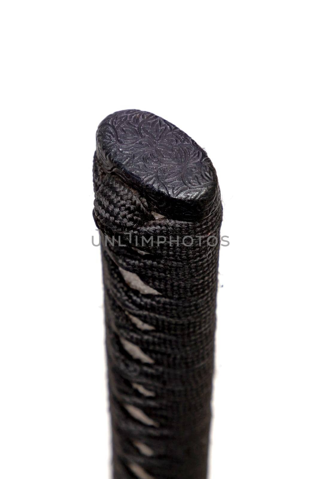 Close up the Kashira: butt cap (or pommel) made of steel on the end of the black silk cord wrapped handle Japanese sword isolated in white background. Selective focus.