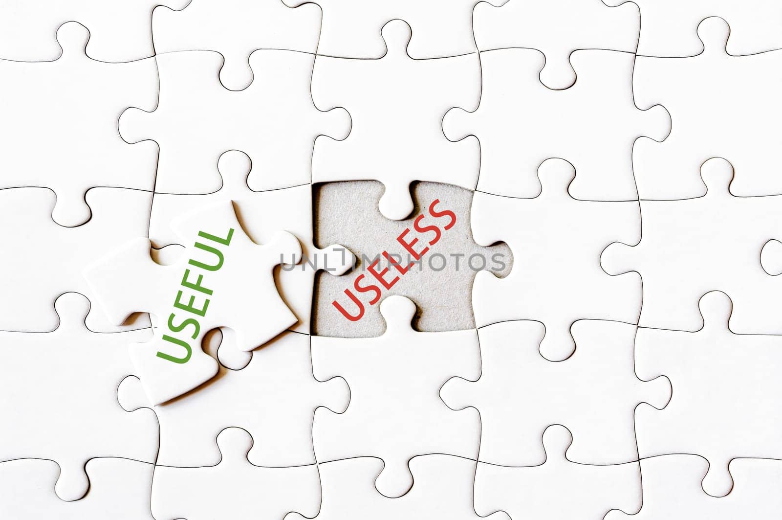 Missing jigsaw puzzle piece with word USEFUL, covering text USELESS. Business concept image for completing the final puzzle piece.