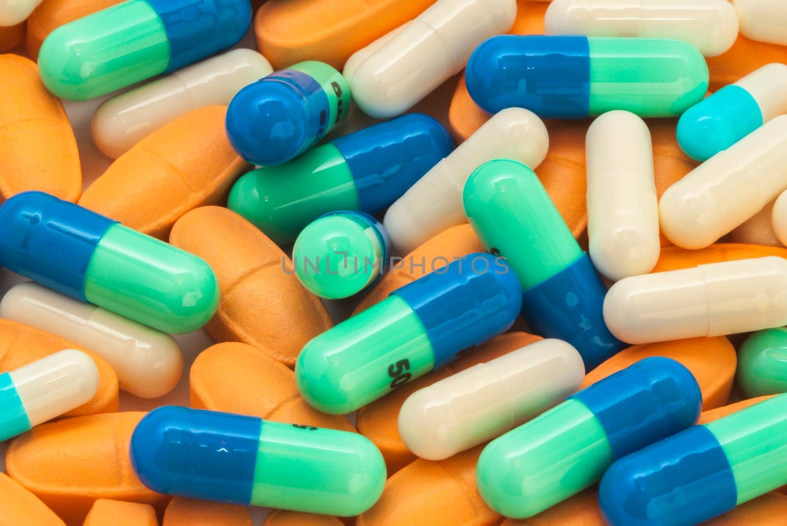 pile of blue-green and orange pills spilling on the table