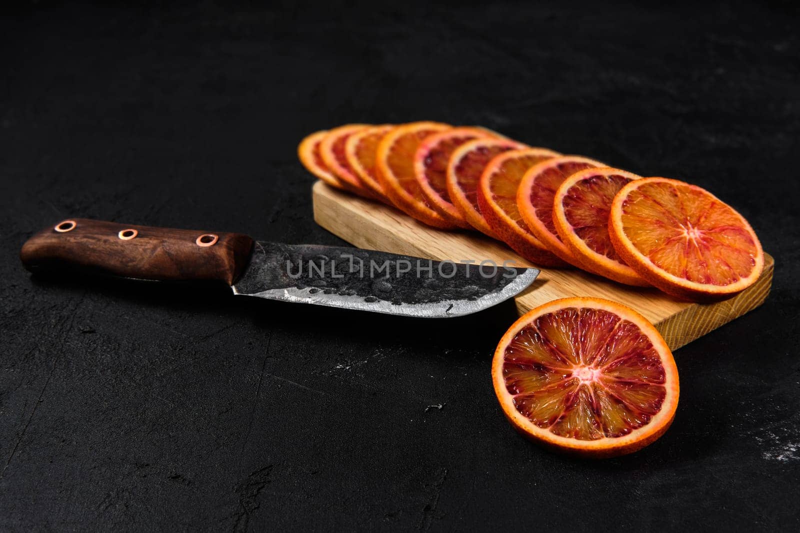 Overhead view of slices of blood orange on black background