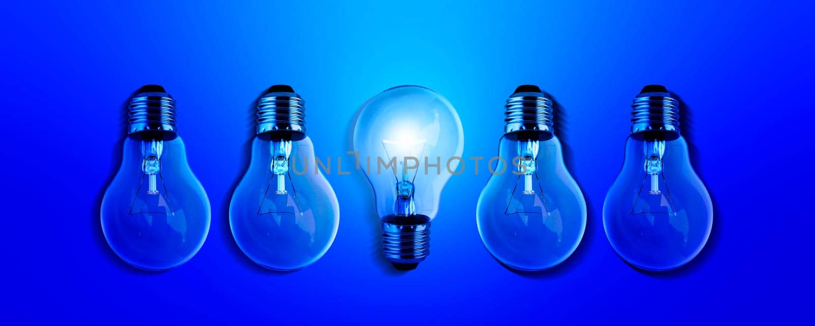 Light bulbs illuminate a row of dim lighting ideas for creativity, innovation and solutions