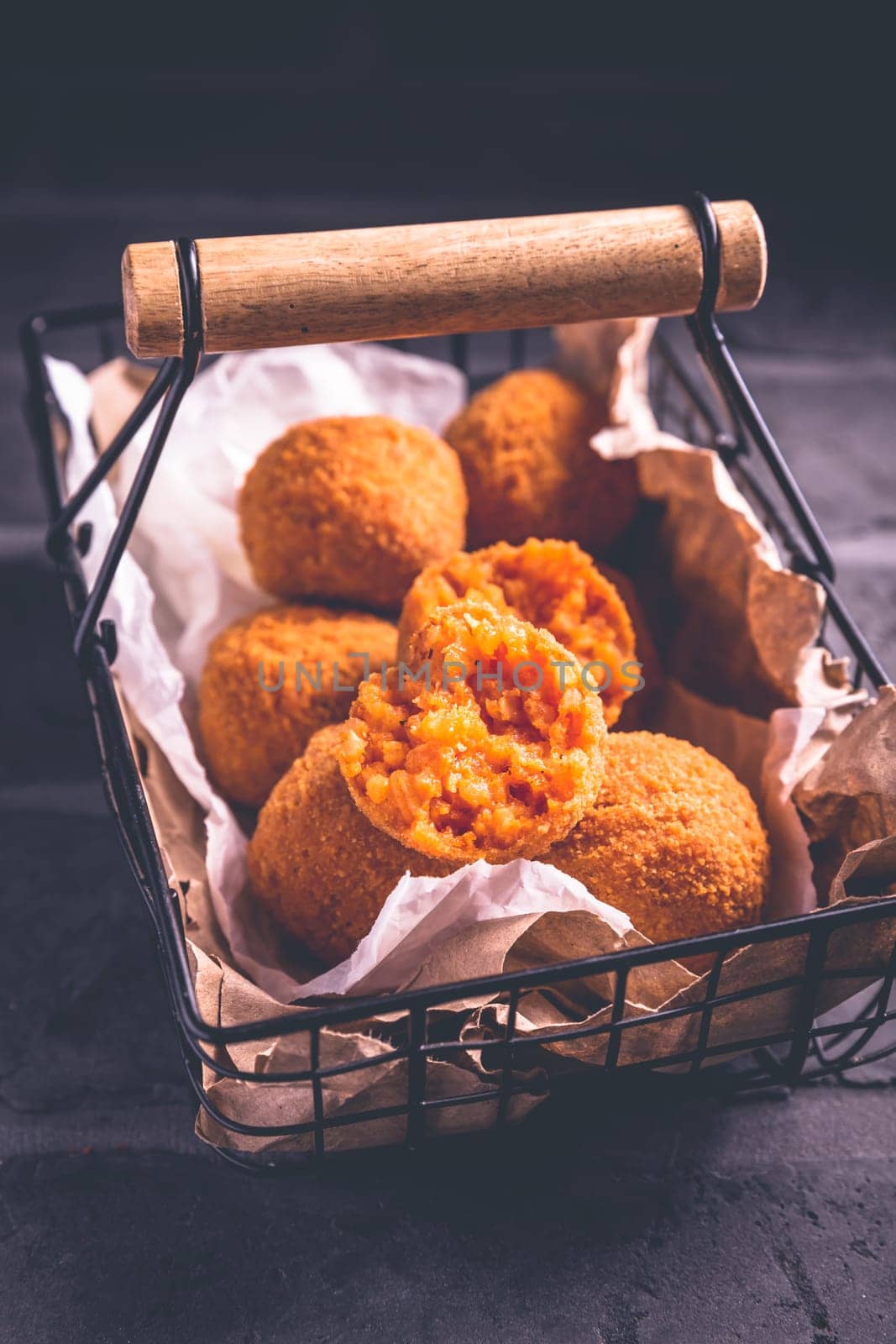 Homemade Arancini - deep fried rice balls stuffed with Mozzarella cheese in basket
