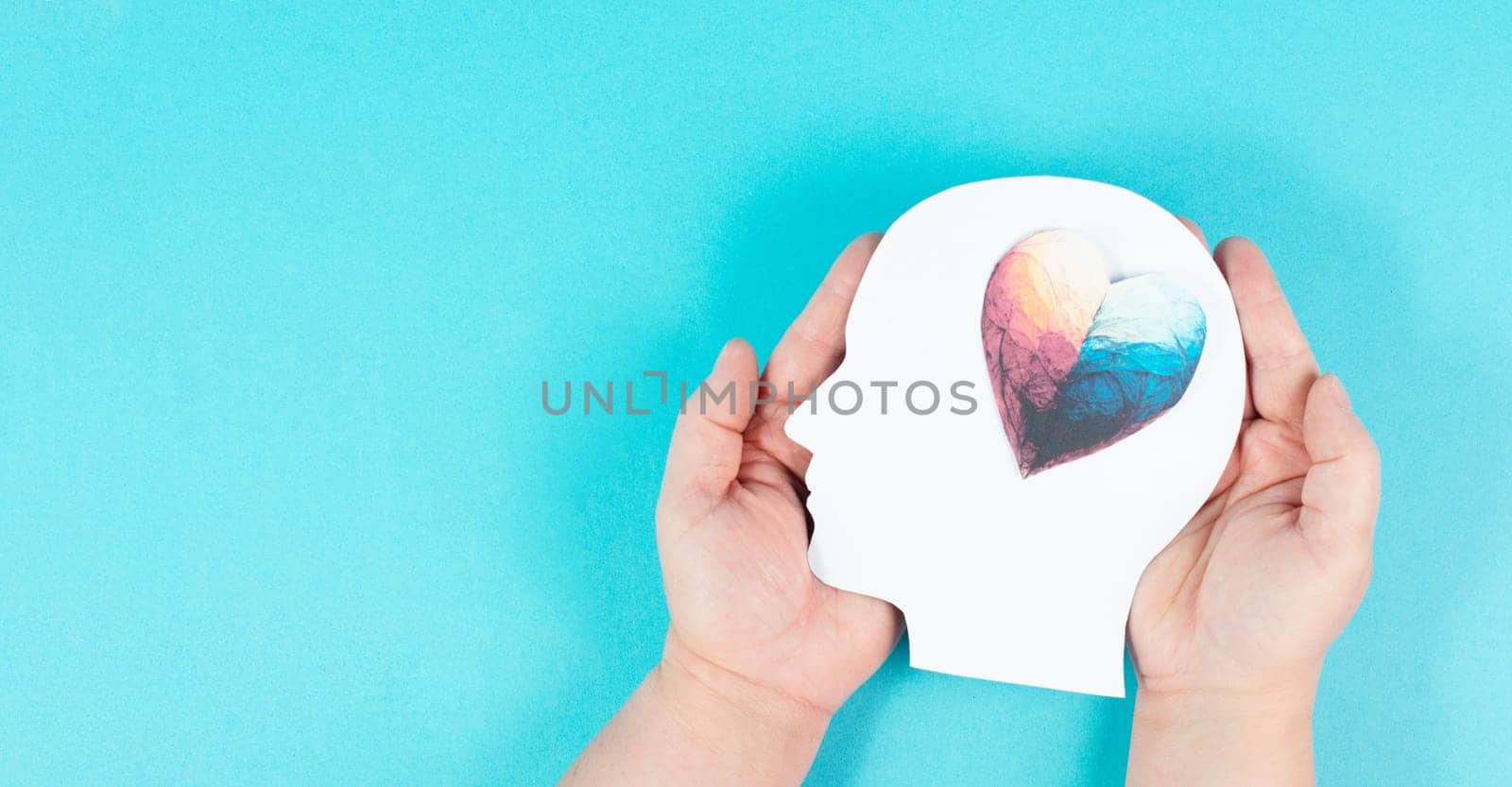 Holding a head with a colorful heart in the hands, symbol of love and positive emotion, charity and support