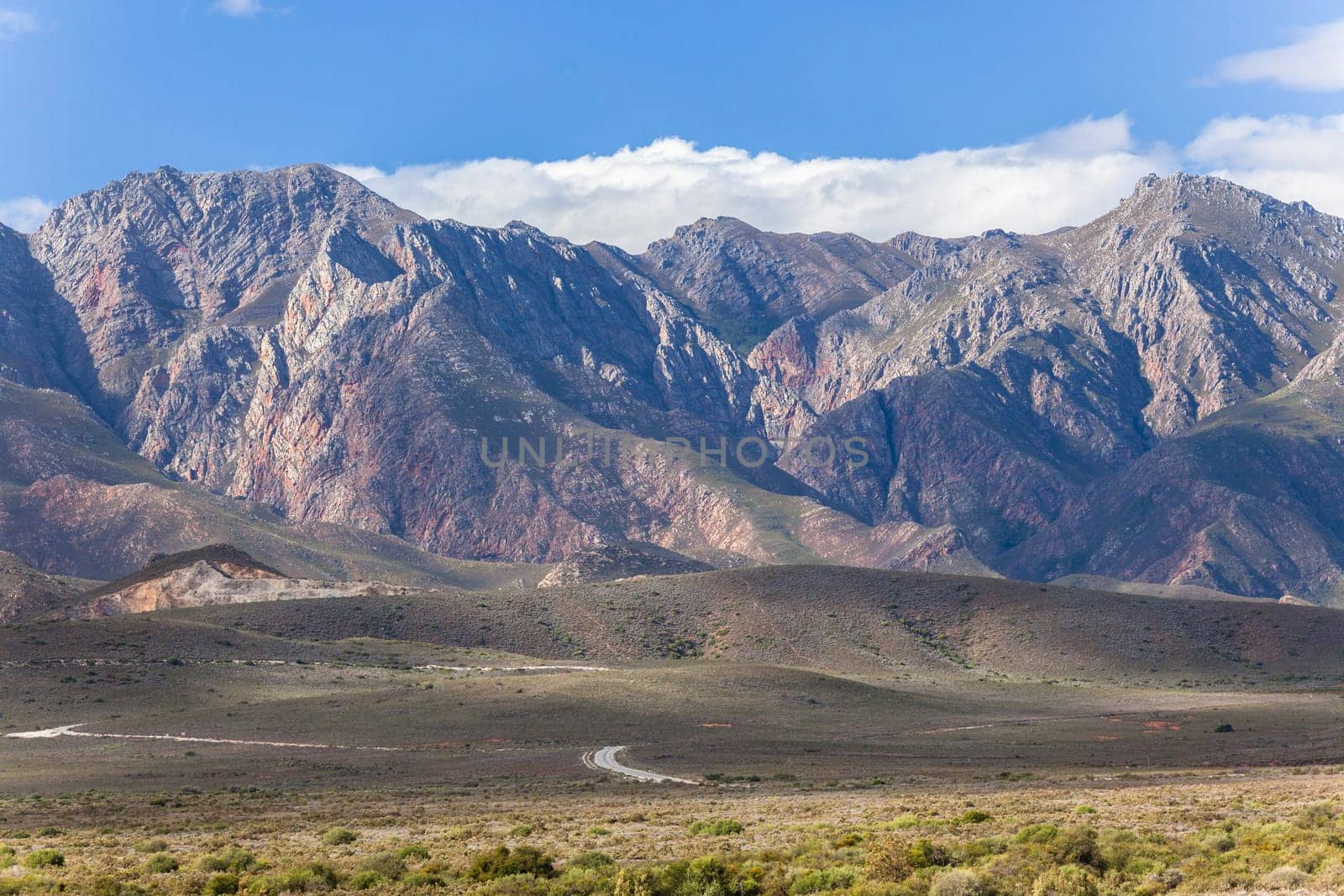 Rocky mountains with winding road on plateau  with green vegetation in karoo wilderness South Africa