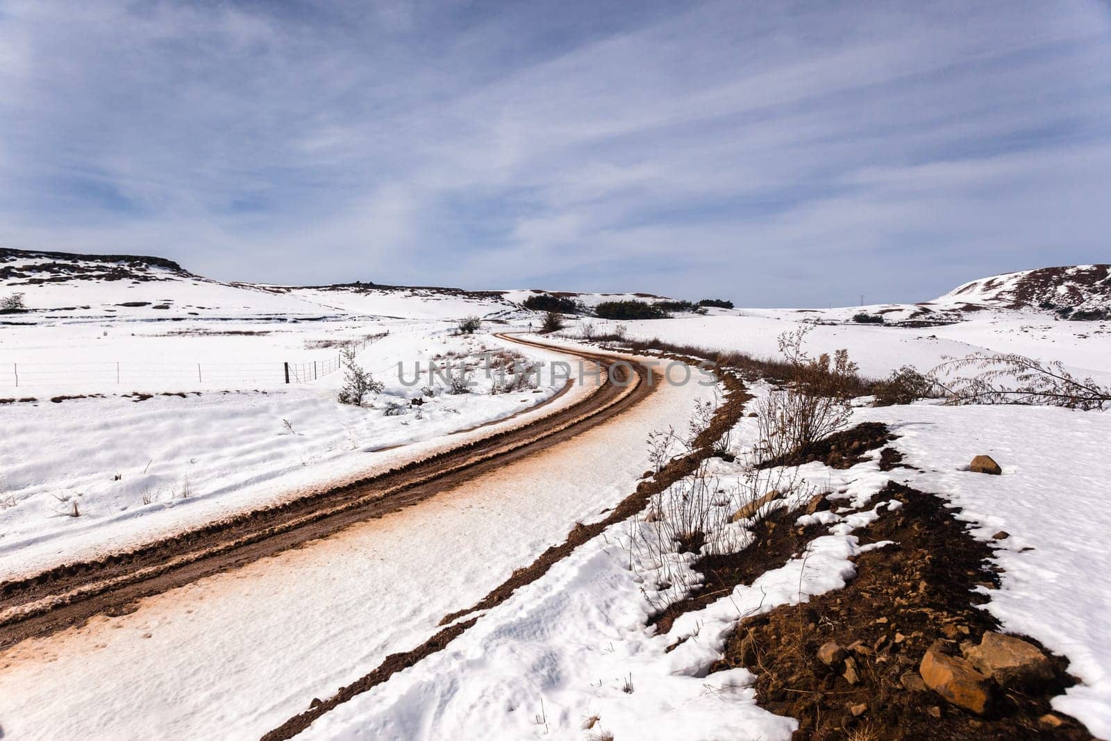 Dirt road tracks over  high plateau mountain terrain in winter snow scenic landscape