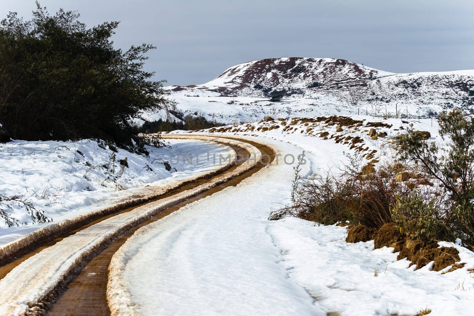 Dirt road tracks over  high plateau mountain terrain in winter snow scenic landscape