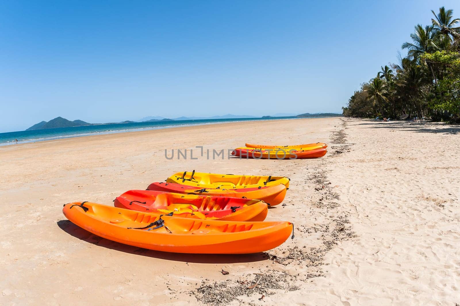 Kayak canoes on beach next to tropical blue ocean water at Mission beach south of Cairns Queensland Australia