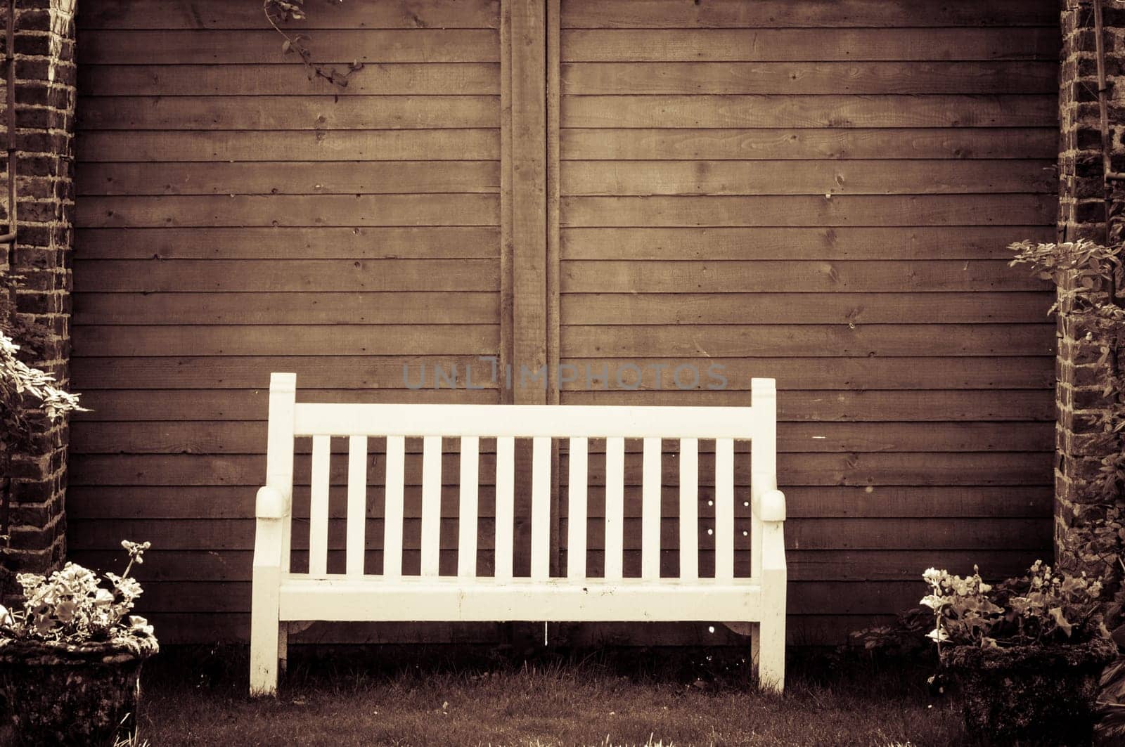 White Wooden garden bench in English garden, retro color filter applied